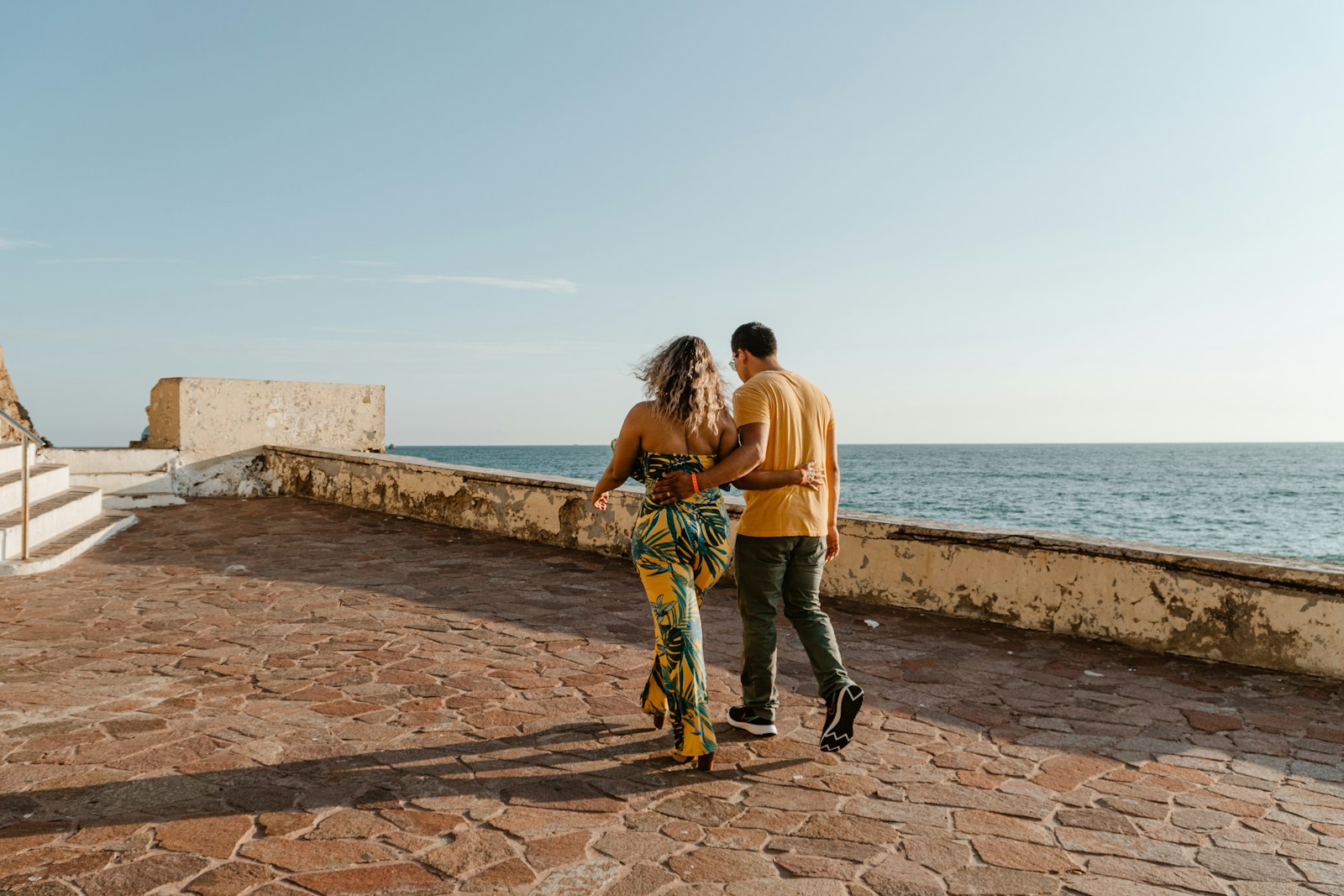 A couple walking together by the ocean in warm evening light